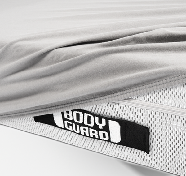 Photo : gros plan sur les poignées du matelas BODYGUARD avec une partie recouverte du drap-housse en flanelle gris  BODYGUARD