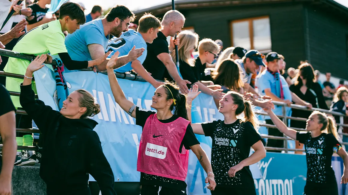 Des joueuses tapent dans la mains des spectateurs dans les tribunes.