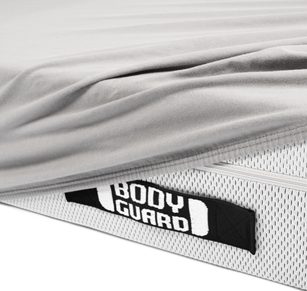 Photo : Gros plan sur une poignée de matelas recourvert d'un drap-housse BODYGUARD gris.  Texte : BODYGUARD.