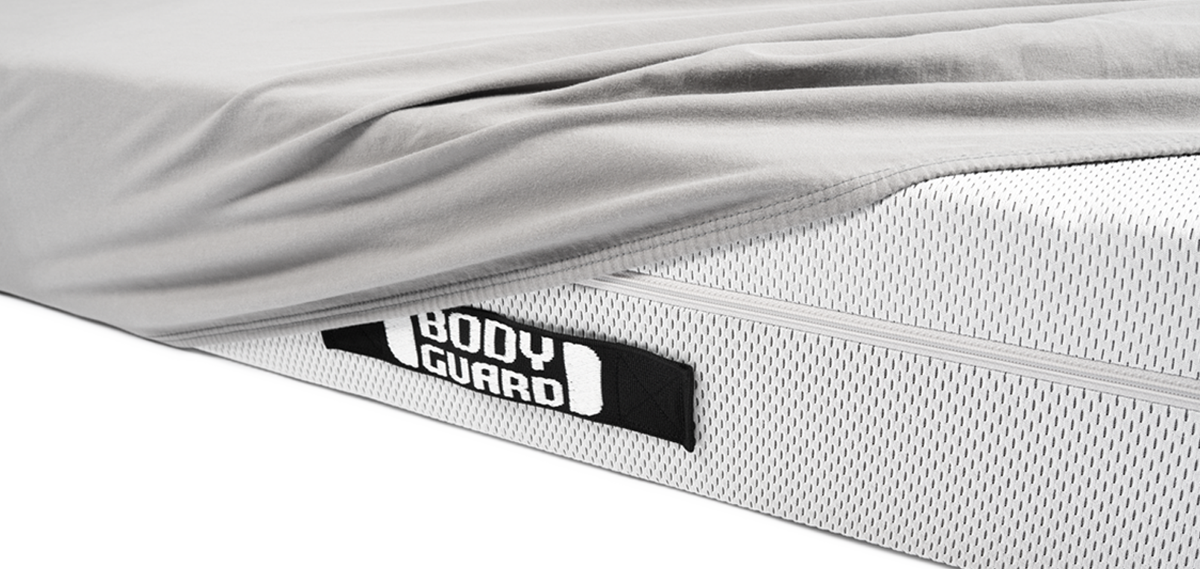Matelas BODYGUARD recouvert à moitié d'un drap housse gris