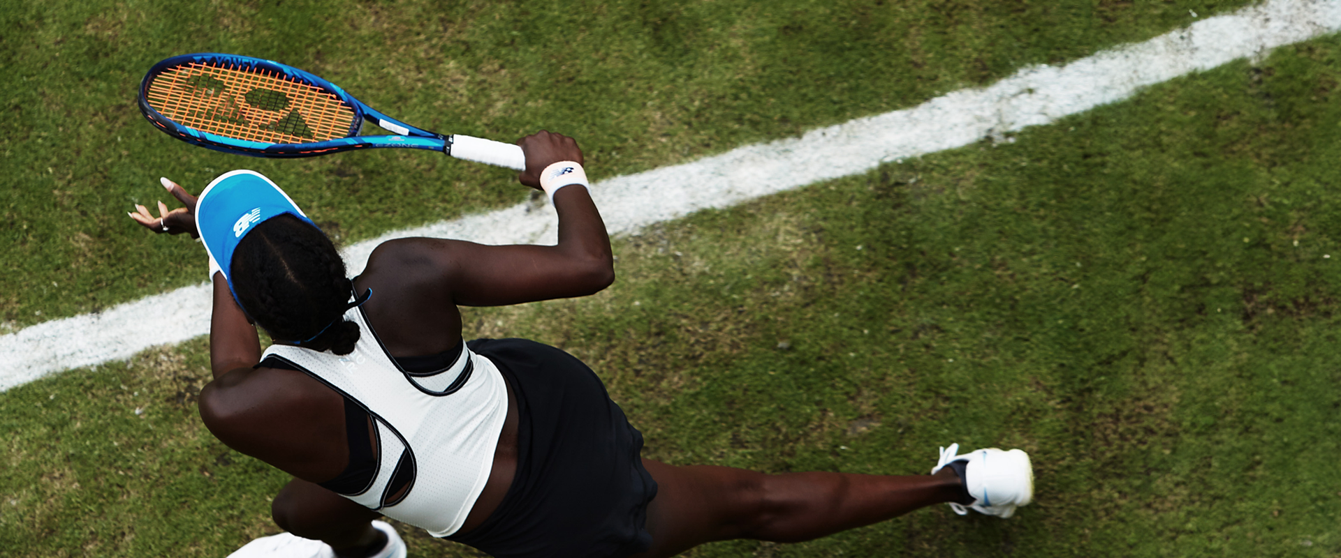 Joueuse de tennis en pleine action sur gazon, vue de dessus.