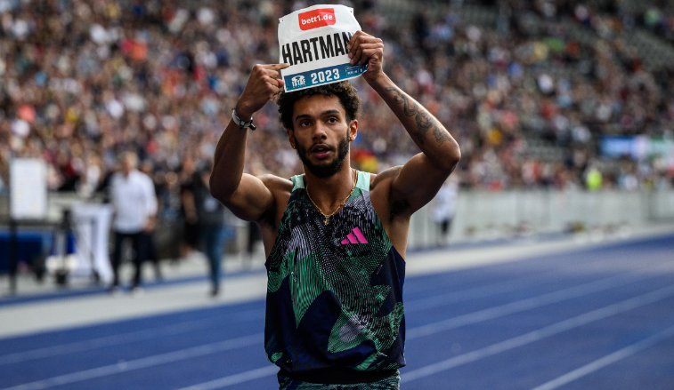 Foto: Ein Läufer auf einer Tartanbahn hält mit beiden Armen ein Schild mit Namen und bett1-Logo über seinen Kopf.