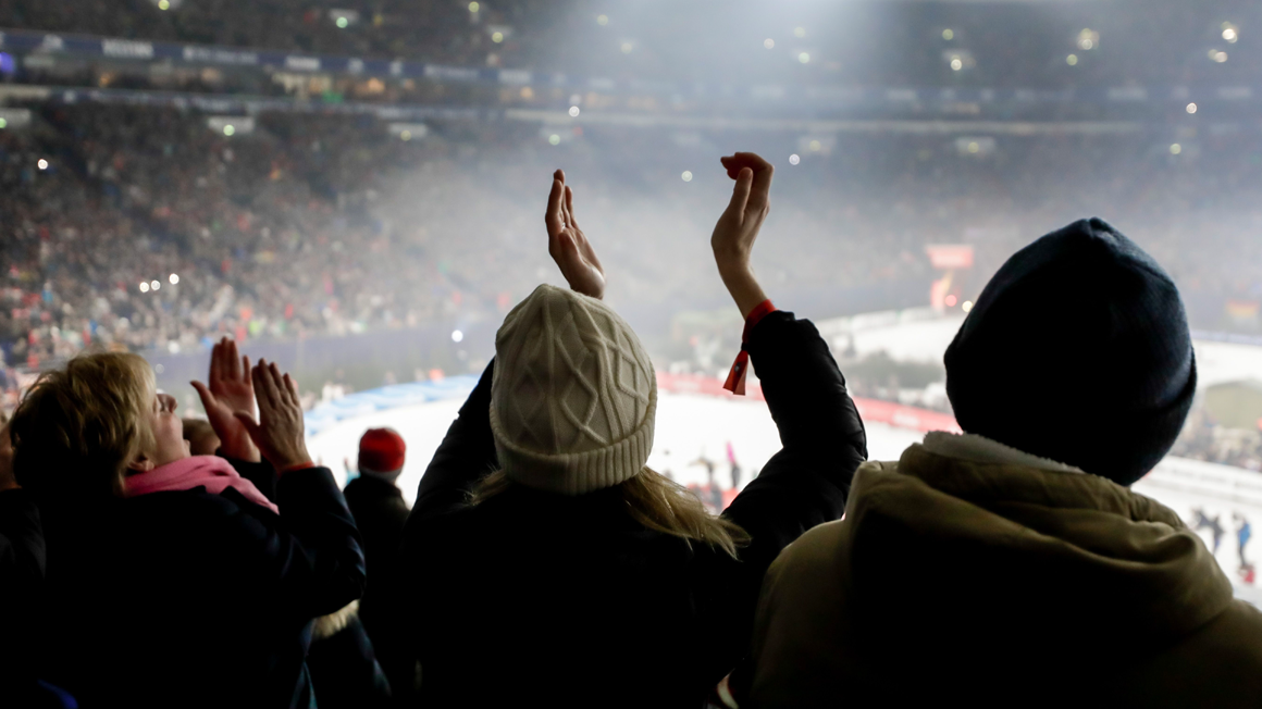 Photo : Un publique de dos applaudit dans un stade