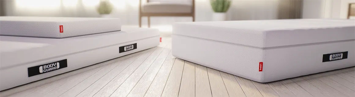 Trois matelas BODYGUARD® posés au sol dans une chambre lumineuse, montrant différentes hauteurs.