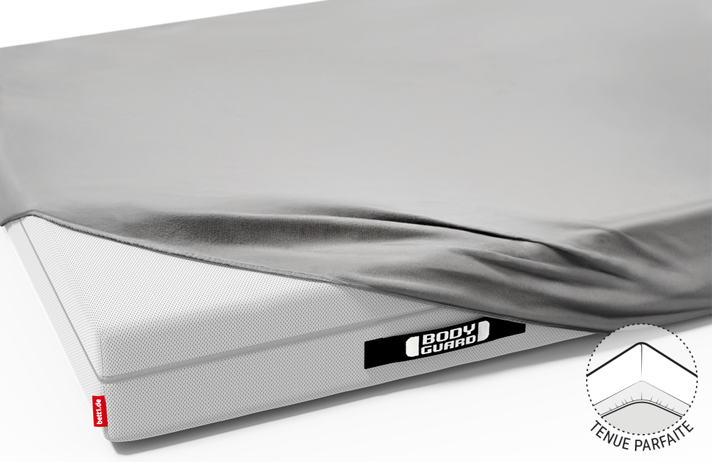 La moitié du matelas BODYGUARD® est recouverte du drap-housse en jersey gris. On voit les poignées noires du Matelas cousues de Bodyguard