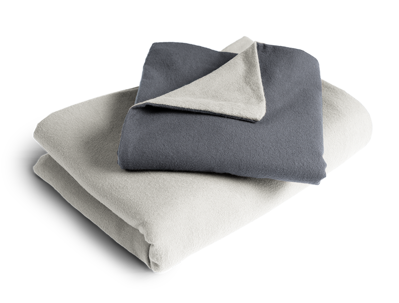 Le linge de lit BODYGUARD® en flanelle plié : la housse de couette est pliée avec la face grise vers l'extérieur, la taie d'oreiller avec la face couleur anthracite.