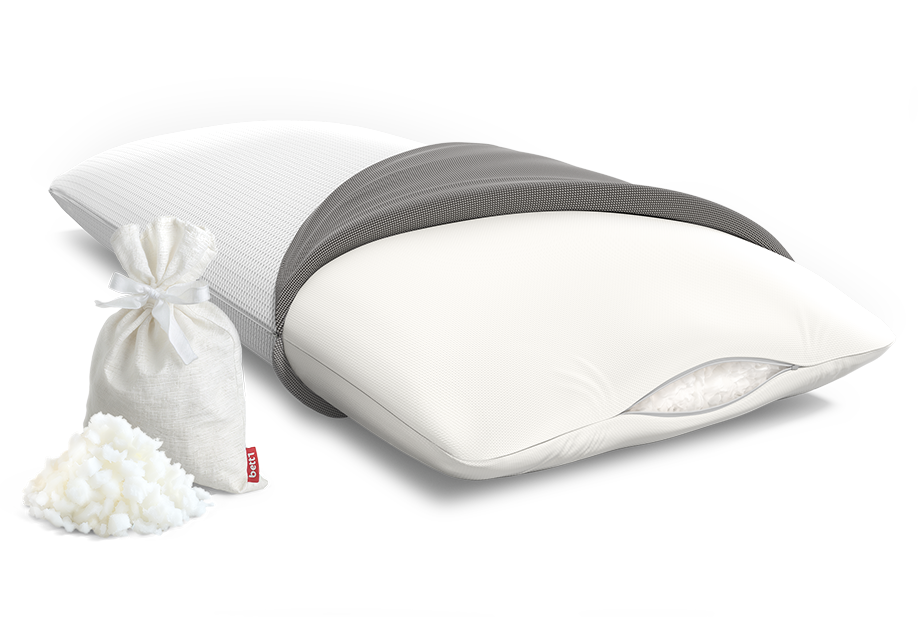 Oreiller Viscoélastique à moitié découvert. Un petit trou laisse apparaître les flocons de mousse. Un petit sachet rempli de flocons de mousse est posé à côté du coussin viscoélastique BODYGUARD avec un tas de flocons à côté.