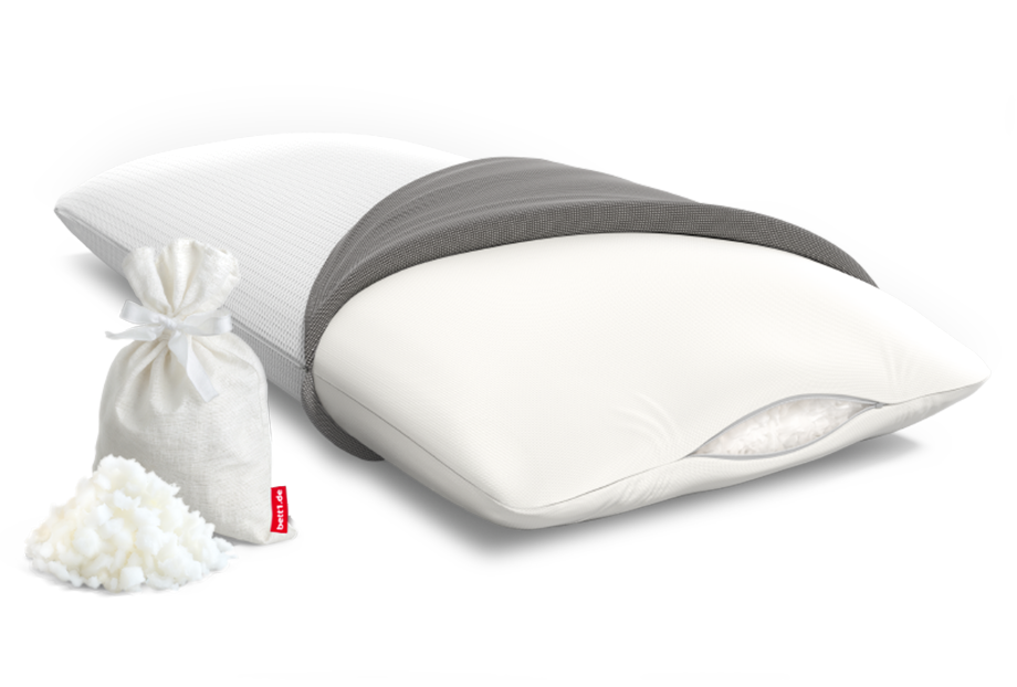 Oreiller Viscoélastique à moitié découvert. Un petit trou laisse apparaître les flocons de mousse. Un petit sachet rempli de flocons de mousse est posé à côté du coussin viscoélastique BODYGUARD avec un tas de flocons à côté.