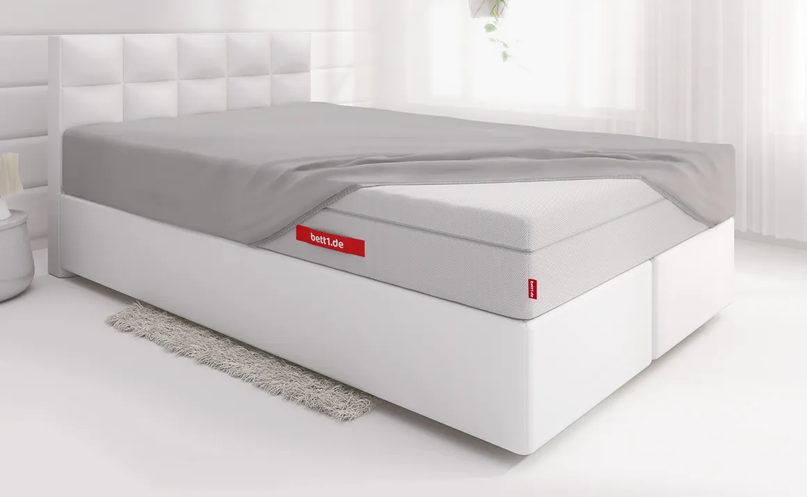 Lit avec un drap-housse BODYGUARD® recouvre une partie du matelas FLIP®. 
