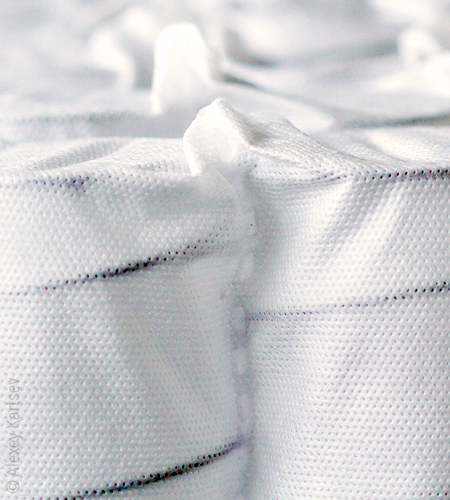 Des ressorts métalliques sombres se distinguent sous un tissu légèrement transparent.
