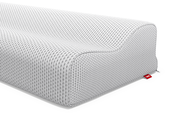 Gros plan sur un oreiller ergonomique Bodyguard à texture alvéolée, présentant une forme ondulée pour soutenir la tête et la nuque. Une petite étiquette rouge est visible sur le côté de la housse.