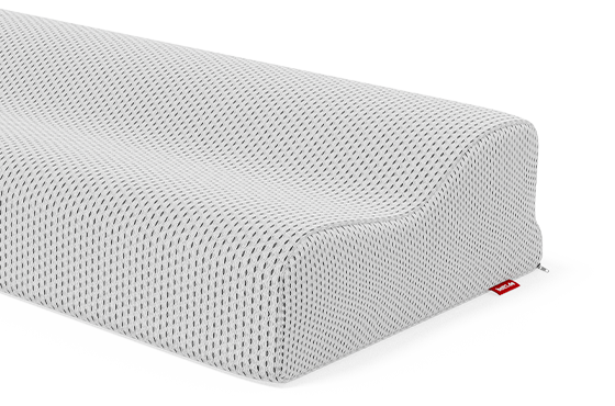 Gros plan sur un oreiller ergonomique Bodyguard à texture alvéolée, présentant une forme ondulée pour soutenir la tête et la nuque. Une petite étiquette rouge est visible sur le côté de la housse.
