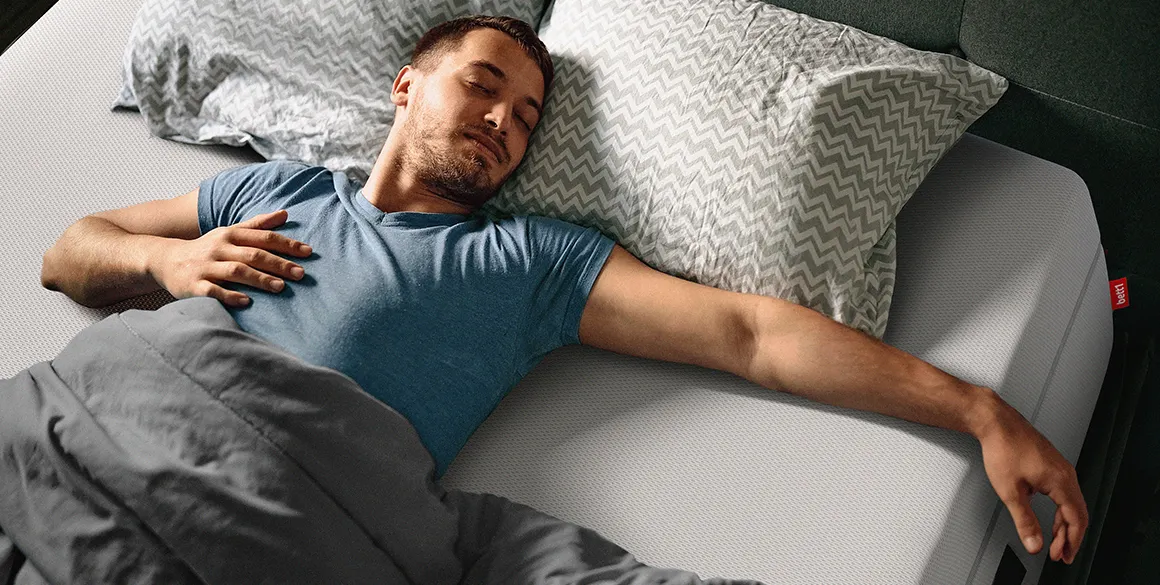 Homme endormi sur un matelas BODYGUARD®, allongé sur le dos et les bras écartés, profitant d’un sommeil paisible.