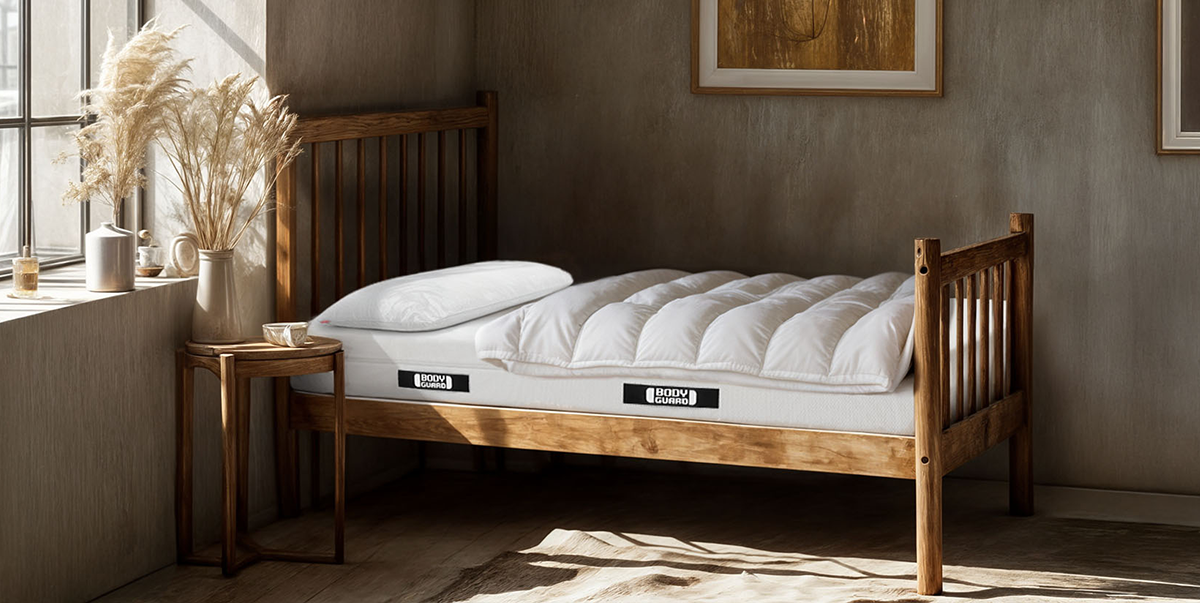 Un lit en bois dans une chambre lumineuseavec un amtelas BODYGUARD, une couette et un oreiller