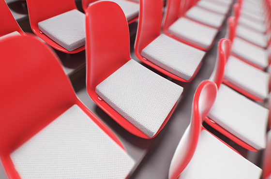 Vue d’ensemble de plusieurs coussins de chaise BODYGUARD® installés sur des sièges rouges en plastique, disposés en rangées comme dans un auditorium ou une salle de conférence.