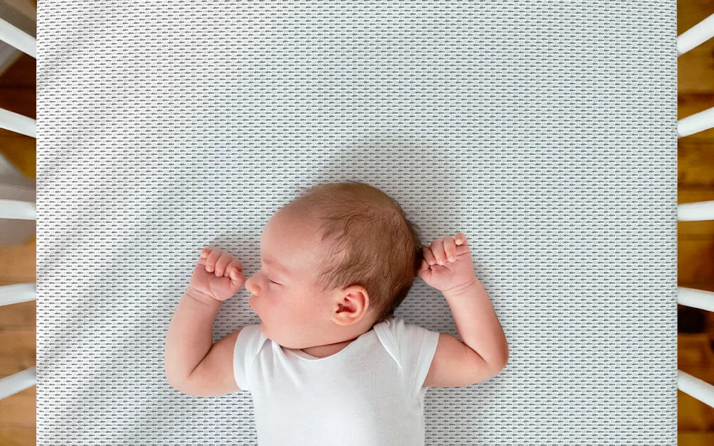 Gros plan sur un bébé debout dans un lit à barreaux sur un matelas enfant BODYGUARD