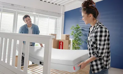 Deux personnes installant un matelas BODYGUARD® sur un sommier à lattes