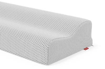 Gros plan sur un oreiller ergonomique Bodyguard à texture alvéolée, présentant une forme ondulée pour soutenir la tête et la nuque. Une petite étiquette rouge est visible sur le côté de la housse.